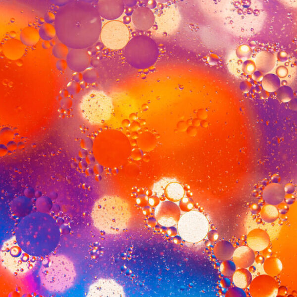Abstract macro photography. Abstract background. Orange with purple color. Distortions in water with drops of oil. Bright abstraction, ultraviolet. Circles on the water